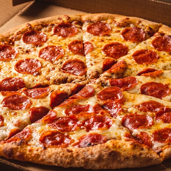 A whole pepperoni pizza with melted cheese and crispy crust in a cardboard box.